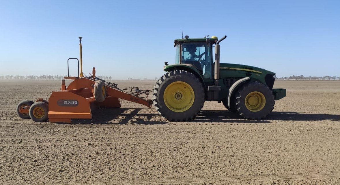 Tractor con pala niveladora trabajando en un lote nivelado según el diseño