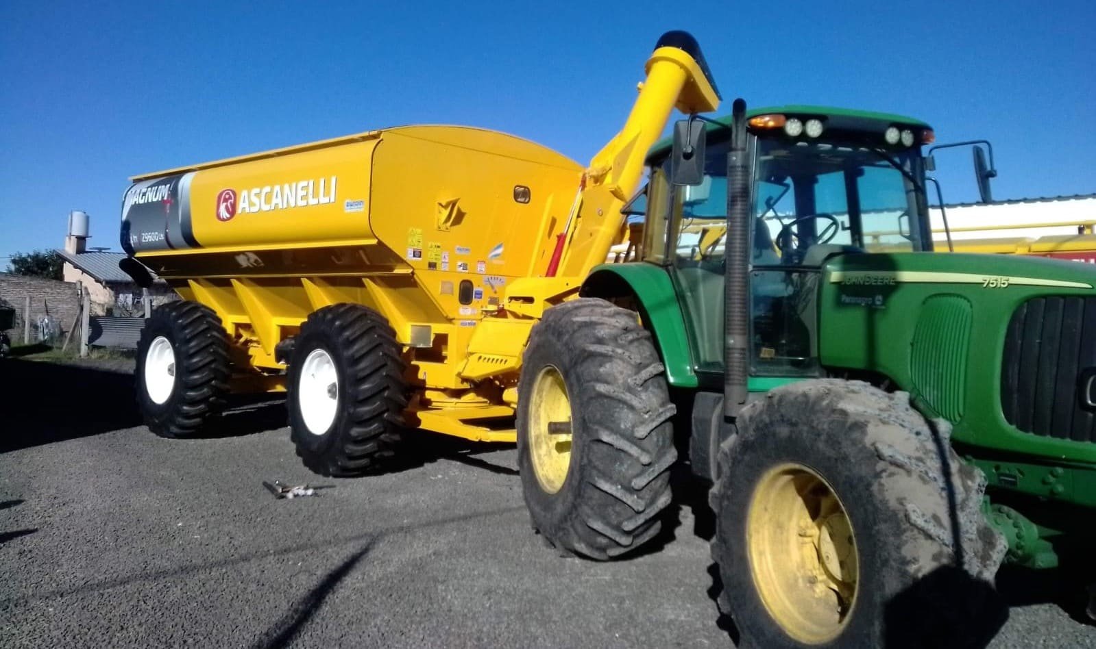 Tolva autodescargable Ascanelli amarilla junto a un tractor John Deere