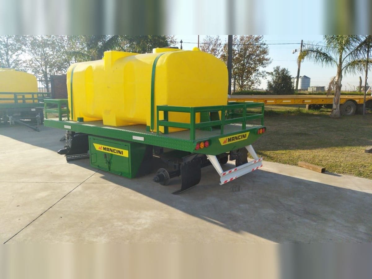 Acoplado playo Mancini verde con tanques rotomoldeados amarillos de apoyo para fumigadora