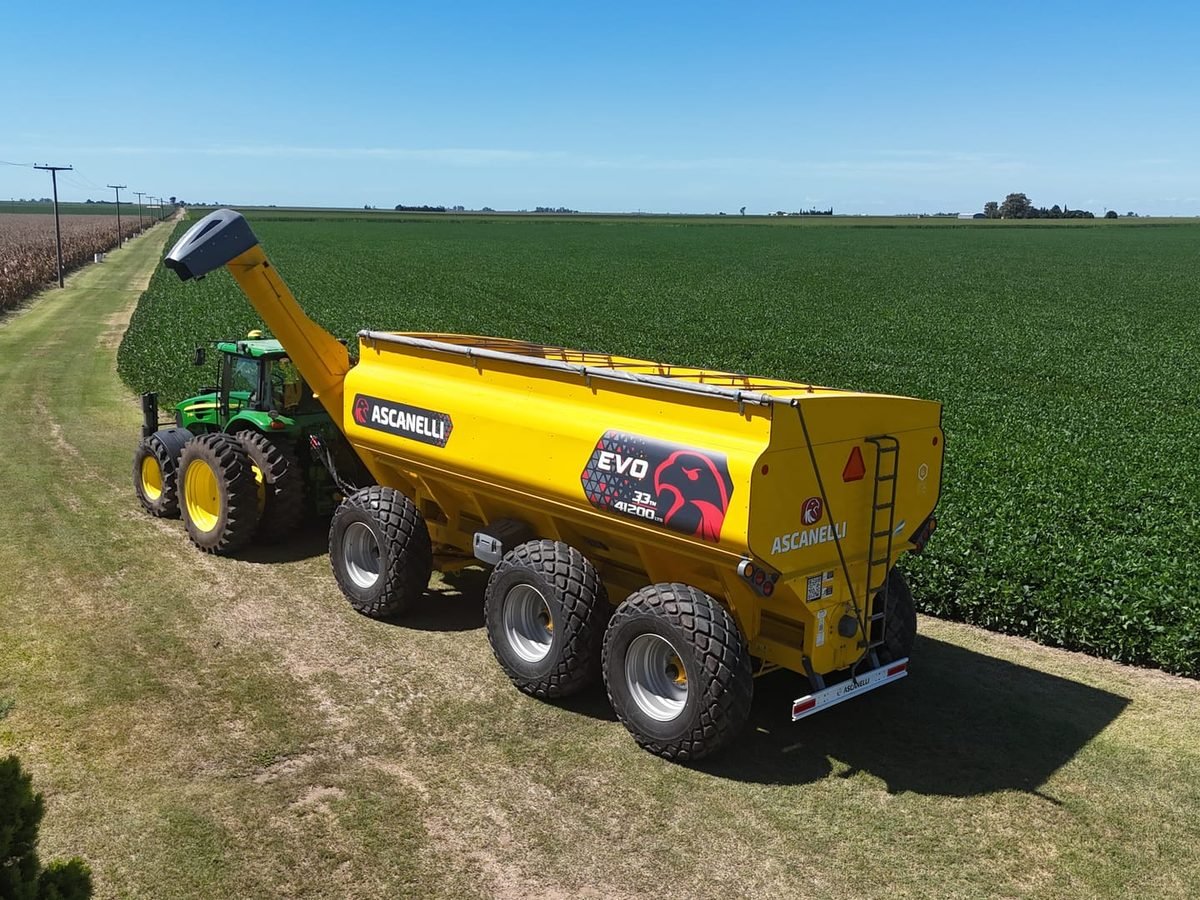 Tolva Ascanelli EVO 33 de 6 ruedas tirada por un tractor junto a un lote sembrado