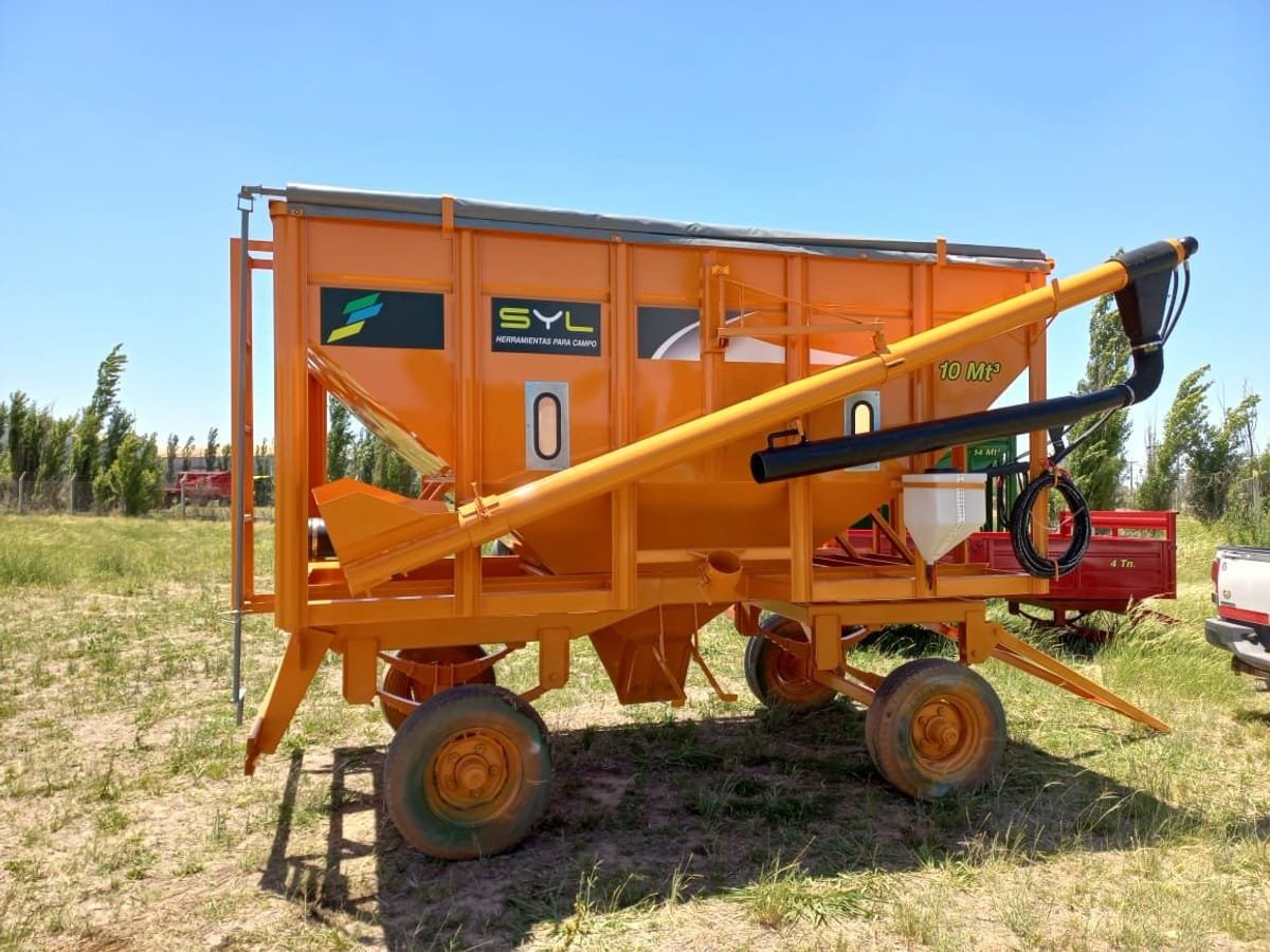Tolva semilla-fertilizante SYL naranja de 10 m³ con chimango, en el campo
