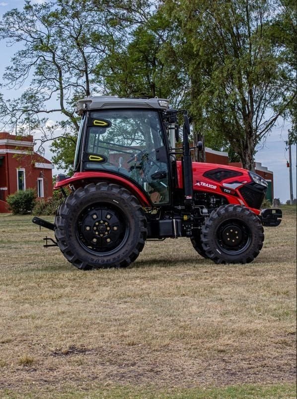 Tractor Traxor TRX 80 con cabina, de costado frente a un casco de estancia